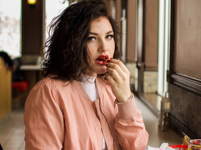 Frau isst Pommes in einem Restaurant | © Unsplash | Guillaume Bolduc