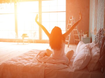 Frau in Yoga-Pose auf dem Bett | © iStock | ArthurHidden