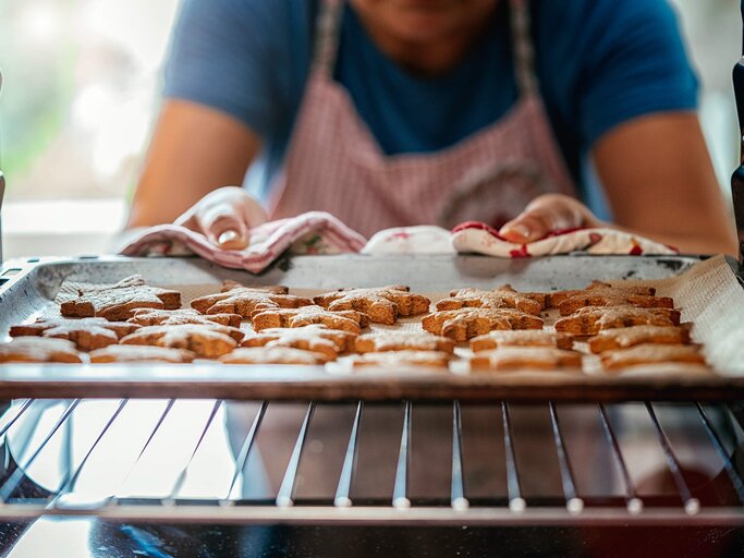 Mann holt Blech mit Plätzchen aus dem Ofen | © iStock | GMVozd
