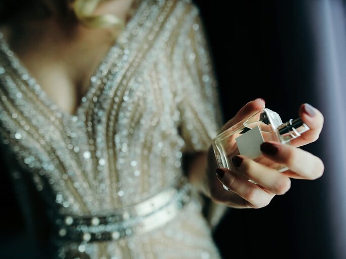 Frau mit Parfum in der Hand | © iStock | Constantinis