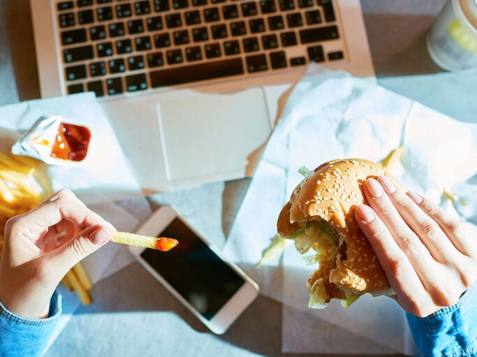 ungesunde Mittagspause mit Burger und Pommes am Laptop | © iStock | mediaphotos