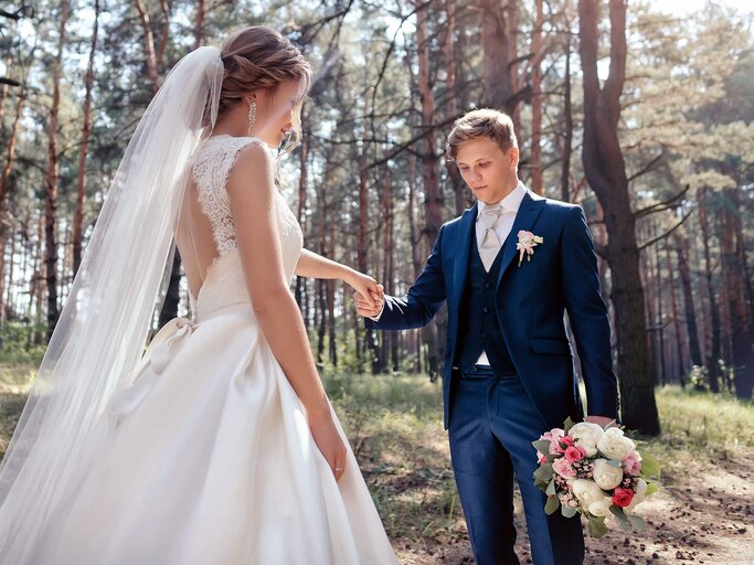 Schönes Brautpaar gehen durch den Wald. | © iStock | shulgenko