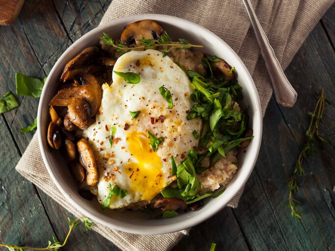 Porridge geht nicht nur süß: Hier die herzhafte Variante - ein Spinat-Pilz-Porridge mit Ei! | © iStock | bhofack2