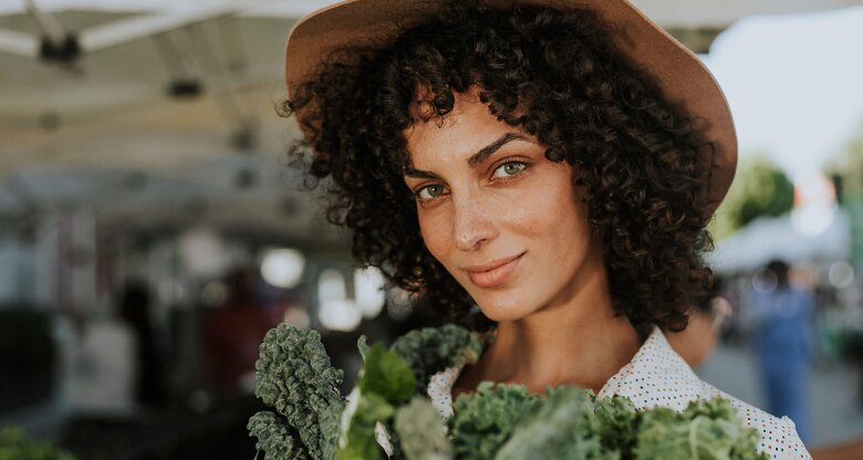 Hübsche, junge Frau auf dem Wochenmarkt mit Grünkohl | © iStock | Rawpixel