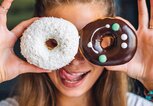 Frau hält sich zwei Donuts vor die Augen | © iStock | macarosha