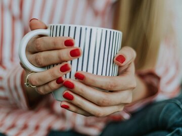 Frau hält Tasse in den Händen und hat makellose mit Shellac manikürte Fingernägel | © Unsplash | Daiga Ellaby