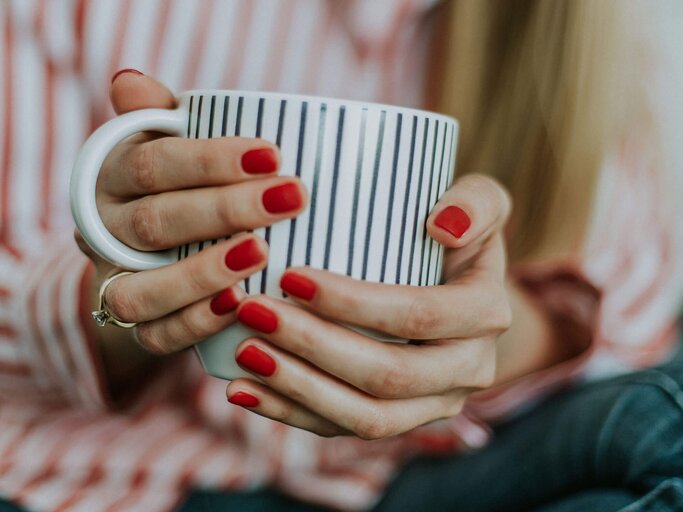 Frau hält Tasse in den Händen und hat makellose mit Shellac manikürte Fingernägel | © Unsplash | Daiga Ellaby