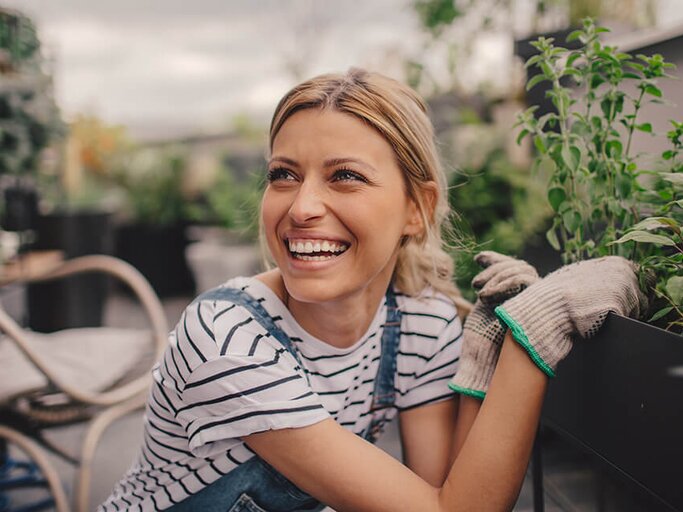 Hübsche junge Frau beim Umpflanzen auf dem Balkon | © iStock | AleksandarNakic
