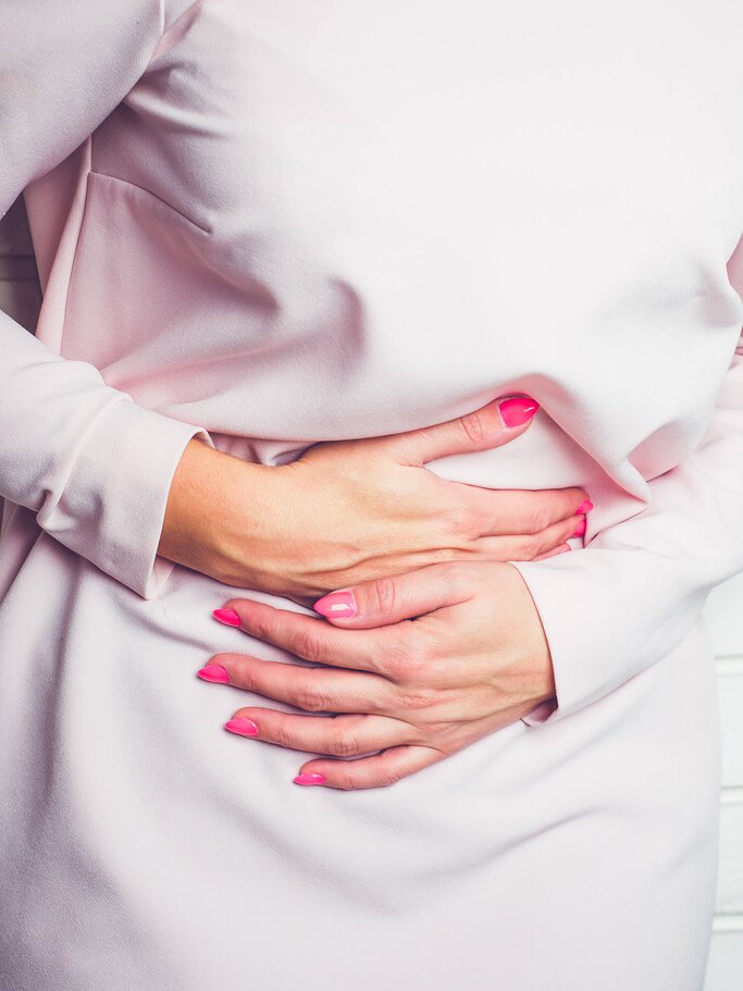 Frau hält sich den Bauch vor Schmerzen | © iStock | Sebastian Gorczowski