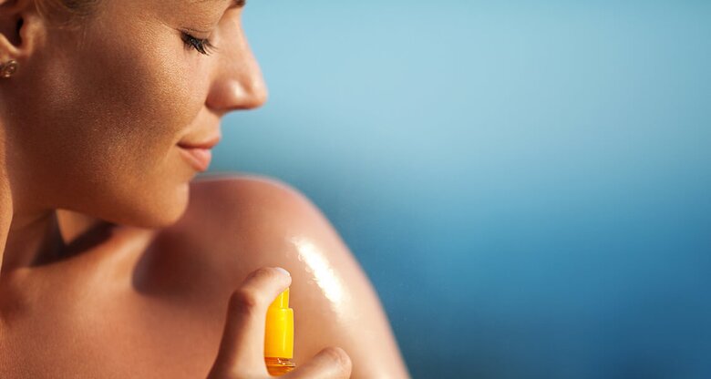 Frau, die gerade Sonnenspray benutzt | © iStock | gilaxia