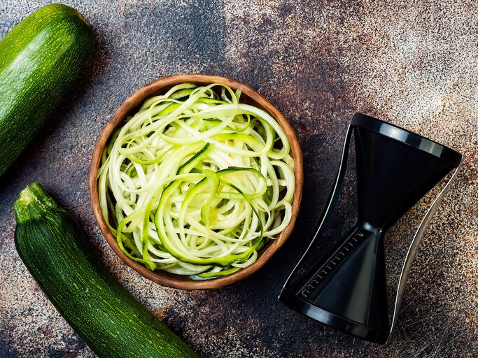 Zucchini Spaghetti in einer Schüssel neben einem Spiralschneider | © iStock | sveta_zarzamora