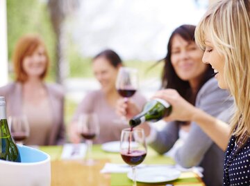 Frau gießt sich ein Glas Rotwein ein. | © imago images / Westend61