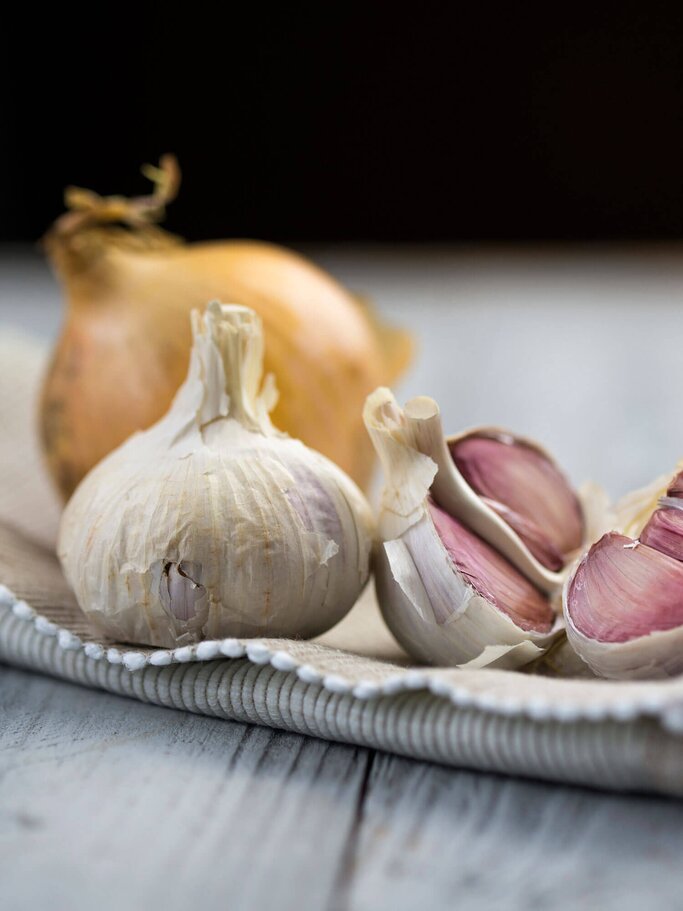 Knoblauch mit einer Zwiebel im Hintergrund | © iStock | Dash_med