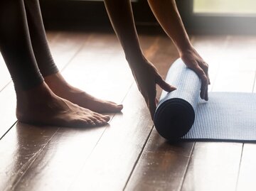 Frau rollt Yogamatte aus | © iStock | fizkes