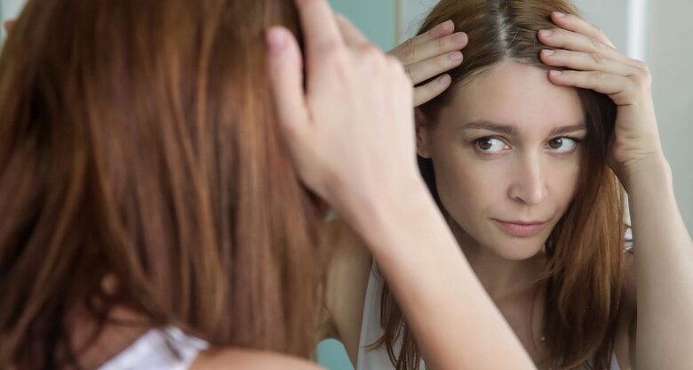 Junge Frau, die Probleme mit juckender Kopfhaut hat, kratzt sich am Hinterkopf. | © iStock | triocean