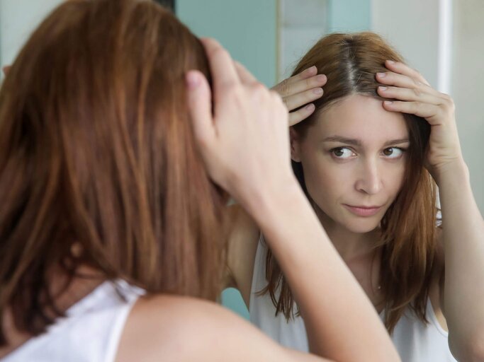 Junge Frau, die Probleme mit juckender Kopfhaut hat, kratzt sich am Hinterkopf. | © iStock | triocean