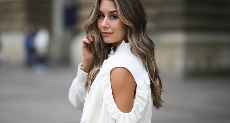 Influencerin Janina Pfau mit Babylights im Haar und Streetstyle mit weißer Bluse in Hamburg  | © Getty Images | Jeremy Moeller