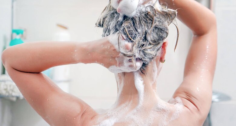 Nahaufnahme einer Frau unter der Dusche, die sich die Haare wäscht. | © iStock | Igor Vershinsky