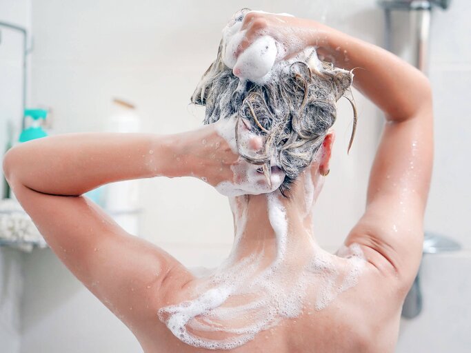 Nahaufnahme einer Frau unter der Dusche, die sich die Haare wäscht. | © iStock | Igor Vershinsky