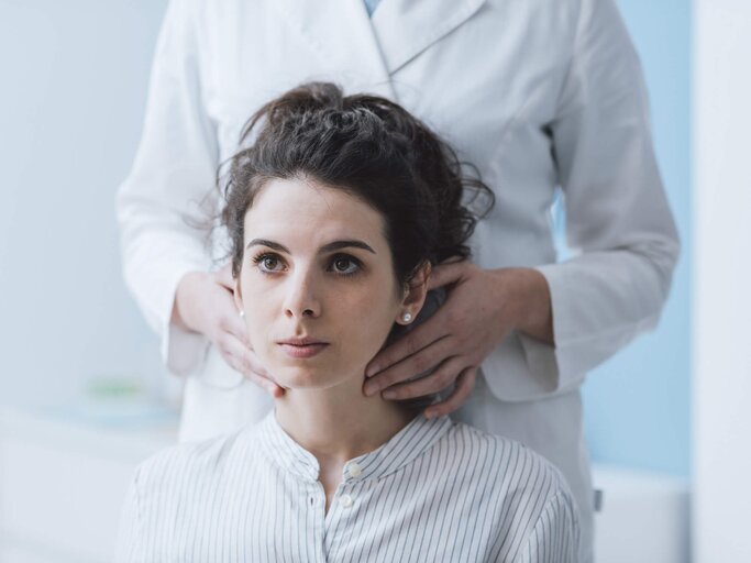 Schilddrüsenunterfunktion: Junge Frau lässt sich bei einem Arzt untersuchen | © iStock | cyano66