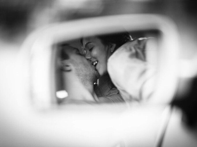Paar küsst sich und man sieht es im Rückspiegel | © iStock | Kontrec