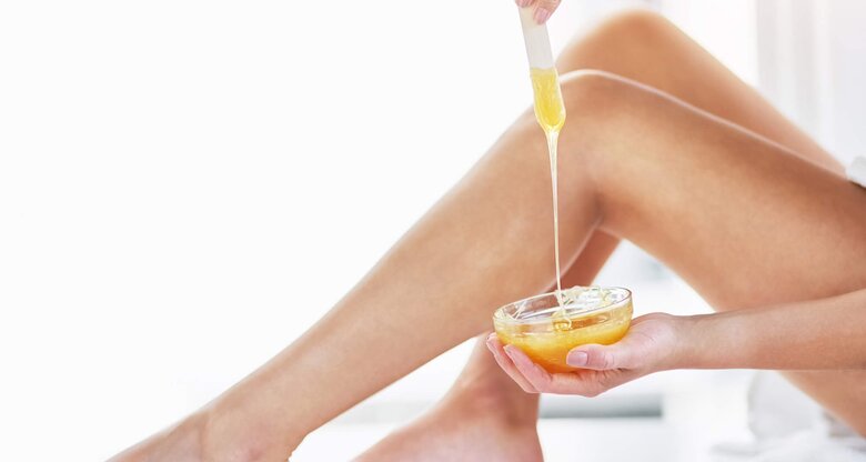 Nahaufnahme eines Beines, das mit Zuckerpaste via Sugaring enthaart wird | © iStock | PeopleImages