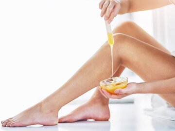 Nahaufnahme eines Beines, das mit Zuckerpaste via Sugaring enthaart wird | © iStock | PeopleImages