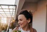 Junge Frau arrangiert Blumen und Pflanzen auf ihrem Balkon | © iStock | AleksandarNakic