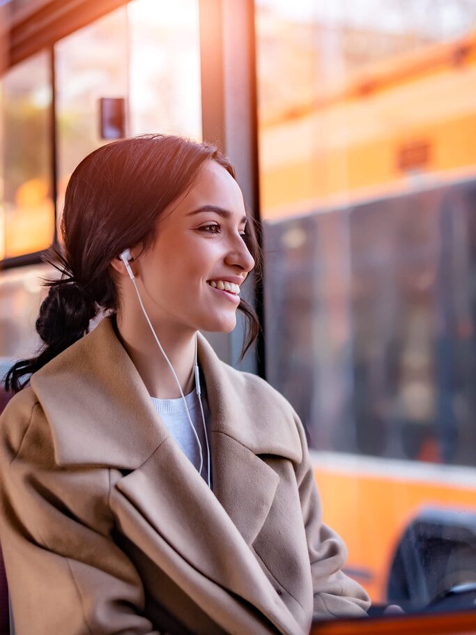 Hübsche junge Frau fährt Bus | © iStock | PredragImages