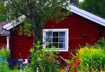 Rotes Holzhaus mit vielen bunten Blumen im verträumten Garten | © iStock | clu