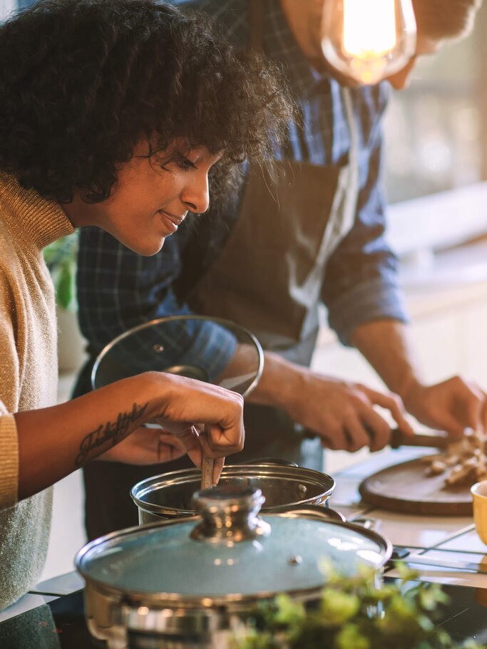 Freunde, die gemeinsam am Herd stehen und kochen | © iStock | vgajic