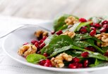 Teller mit einem Spinat-Salat mit Granatapfelkernen und Walnüssen | © iStock | nicolesy