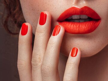 Foto zeigt knallrote Lippen und knallrote Fingernägel in Nahaufnahme | © iStock | CoffeeAndMilk