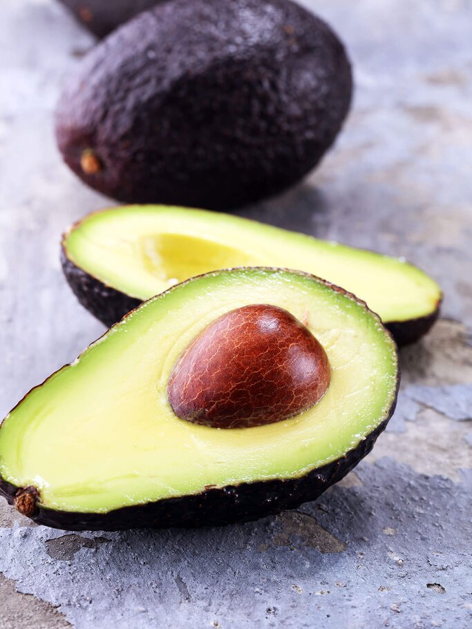 aufgeschnittene Avocado auf einer Steinplatte | © iStock | beats3