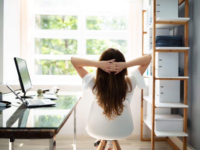 Entspannte Geschäftsfrau sitzt im Büro mit Blick in die Ferne | © iStock | AndreyPopov