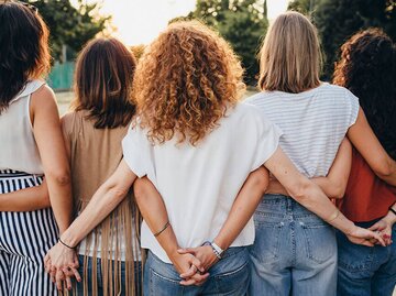 Gruppe von Freundinnen, die sich an den Händen halten, von hinten fotografiert | © iStock | FilippoBacci