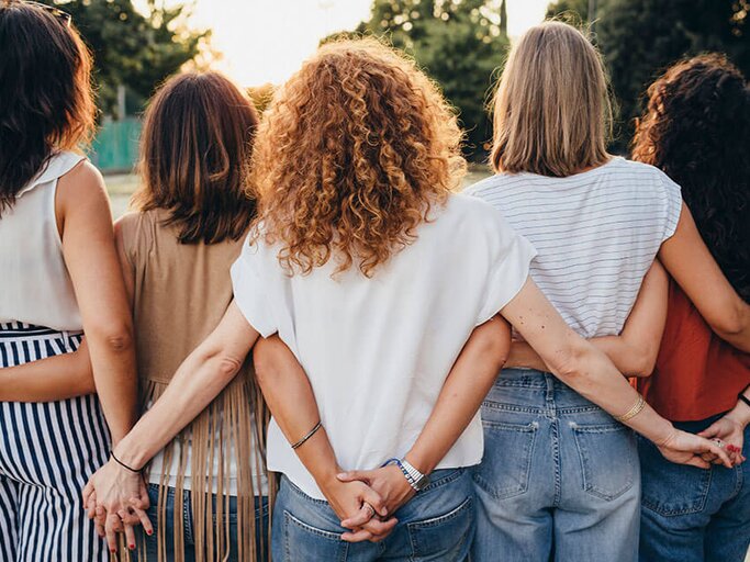 Gruppe von Freundinnen, die sich an den Händen halten, von hinten fotografiert | © iStock | FilippoBacci