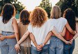 Gruppe von Freundinnen, die sich an den Händen halten, von hinten fotografiert | © iStock | FilippoBacci