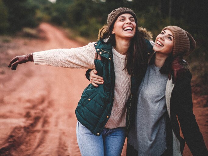 Zwei Freundinnen laufen Arm in Arm durch den Wald | © iStock | StefaNikolic