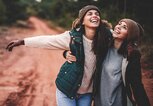 Zwei Freundinnen laufen Arm in Arm durch den Wald | © iStock | StefaNikolic