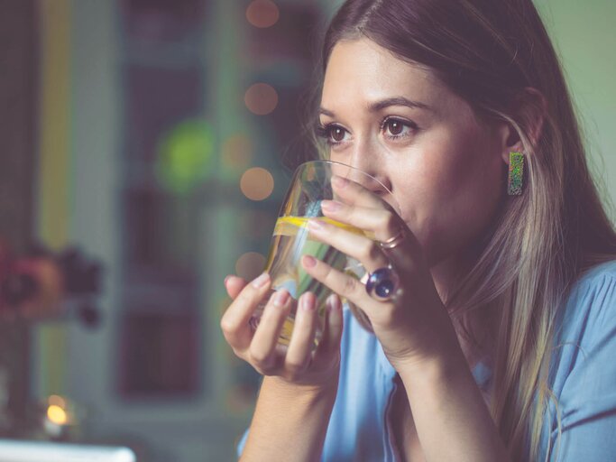 Junge Frau trinkt Glas Wasser mit Zitronenscheibe. | © iStock | Eva-Katalin