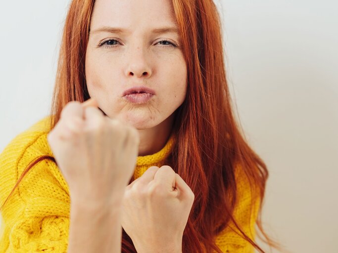 junge Frau mit roten Haaren in kämpferischer Pose | © iStock | stockfour