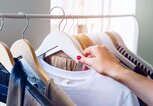 Frau greift einen Kleiderbügel von der Kleiderstange | © iStock | Circle Creative Studio