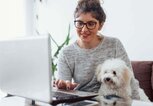 Junge Frau sitzt mit Hund vor dem Laptop | © iStock | Likoper