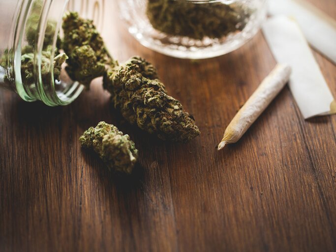 Marihuana in einem Glas, daneben ein Joint | © iStock | MmeEmil
