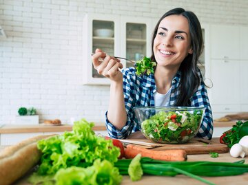 Junge Frau lacht und isst einen Salat | © iStock | Povozniuk