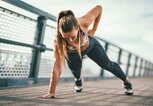 Frau macht einarmige Liegestütze auf einer Brücke. | © iStock | MilanMarkovic