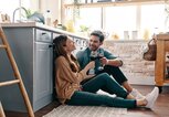 Junges Paar sitzt auf dem Küchenboden und trinkt Wein | © iStock | g-stockstudio
