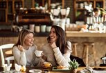 Junge Frauen unterhalten sich im Cafe | © iStock | Drazen Zigic