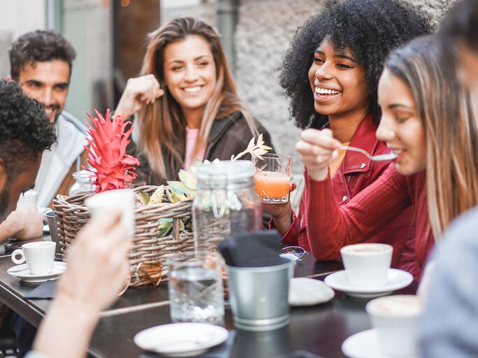 Freunde sitzen gemeinsam in einem Cafe | © iStock | DisobeyArt